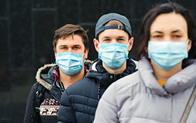 Jugendliche und Erwachsene mit Mund-Nasenschutz, frontal zum Betrachter stehend